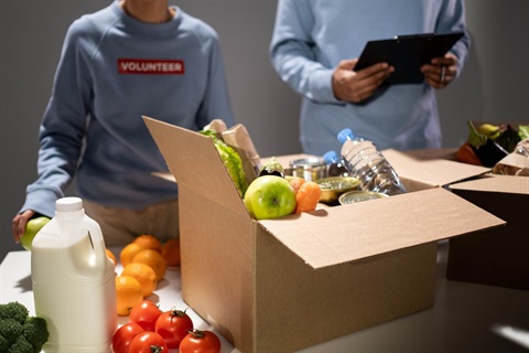 A volunteer fills a box with food and other essentials