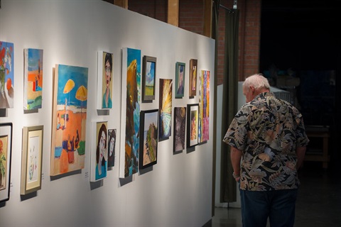 Person looking at paintings installed in Studio Gallery