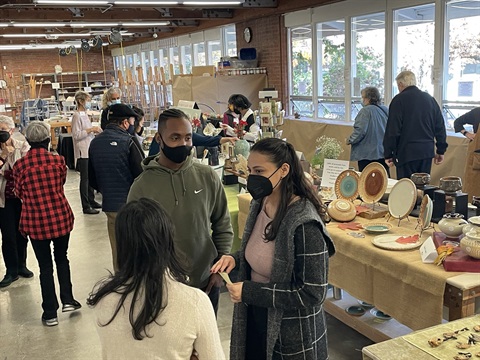 Shoppers at the holiday sale chat and look at ceramics for sale