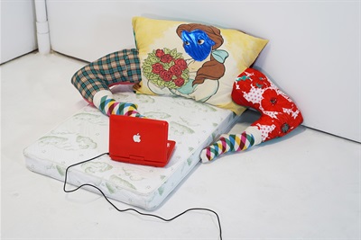 Single mattress and pillow with the face of Disney's Beauty, two stuffed tights that look like legs, and a small red Apple device