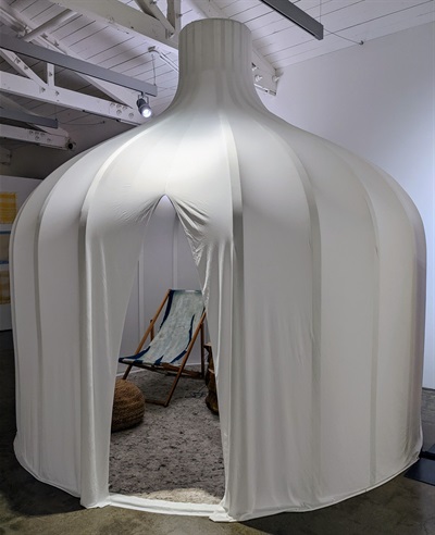 A large white tent-like installation with a deck chair inside