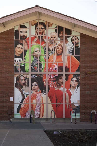 The exterior of the Art Center, featuring a large mural of 12 queer and trans people based in the Bay Area