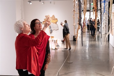 Image of two women looking at an installation of suspended trees