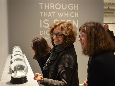 image of group of women looking at snow globe miniature art pieces