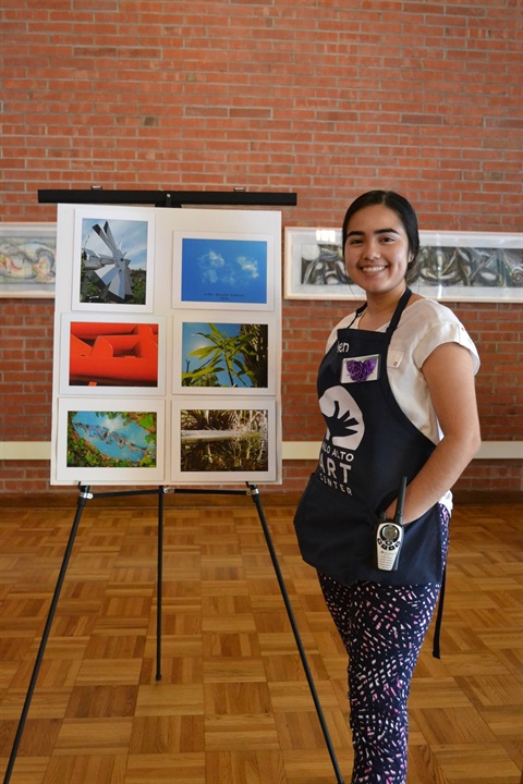 An Art Center's interns in front of a photo display