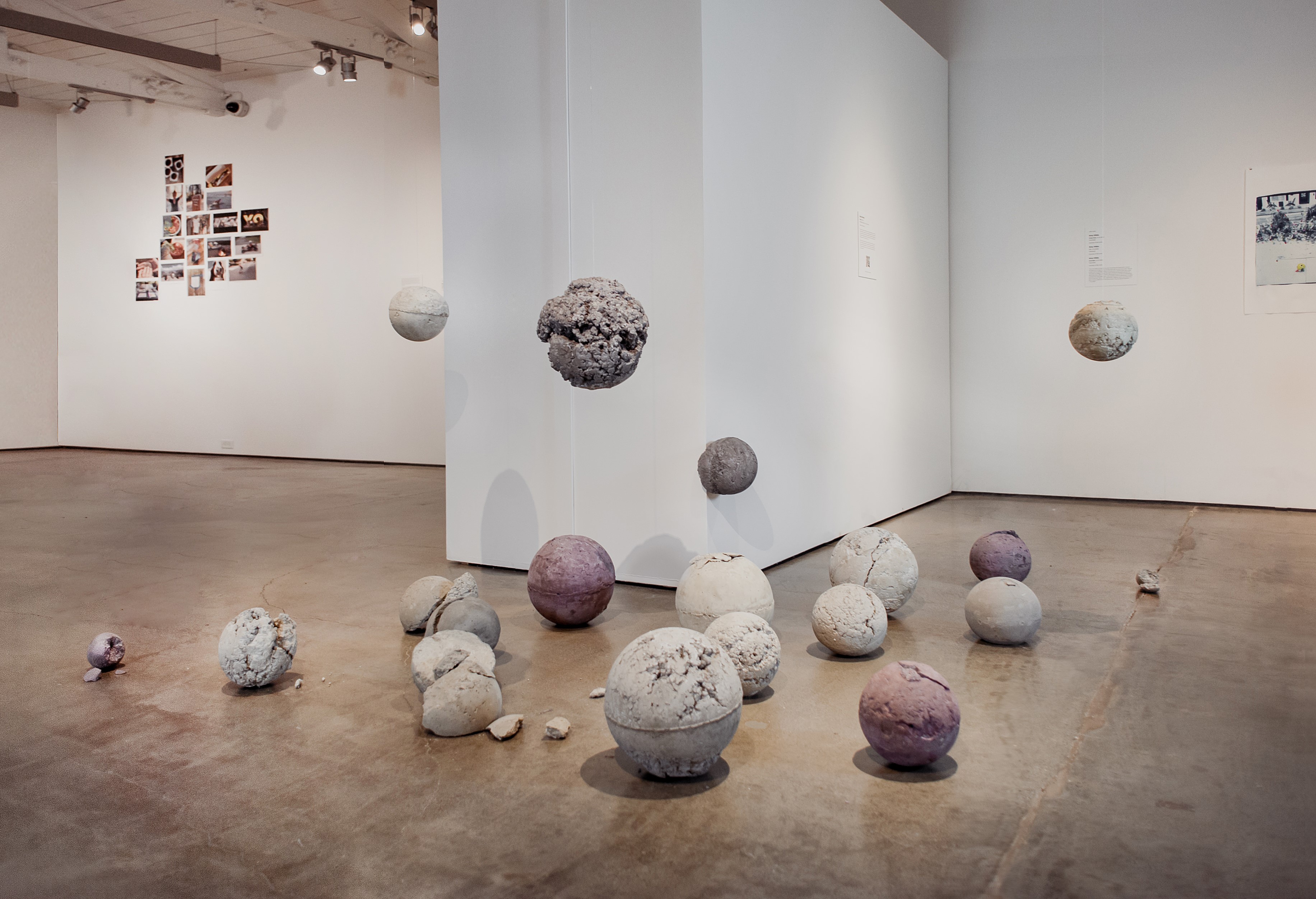 Photo of the installation at the Palo Alto Art Center of Mama?, 19 concrete balls of varying sizes