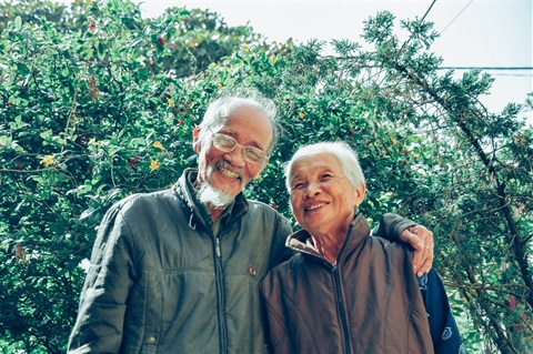 an elderly couple smiles at the camera 