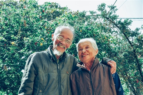 an elderly couple smiles at the camera 