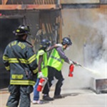 two community emergency response team members using a fire extinguisher to put out a fire