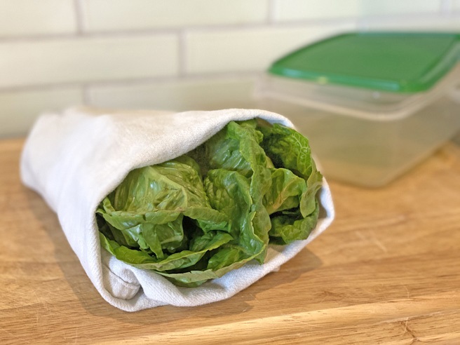 Lettuce wrapped in towel next to storage container