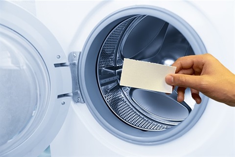 Laundry detergent strip going into washing machine
