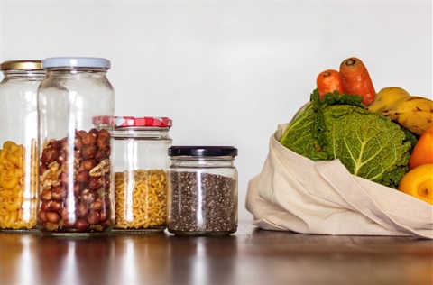 Glass jars with grocery staples and vegetables in a cloth bag