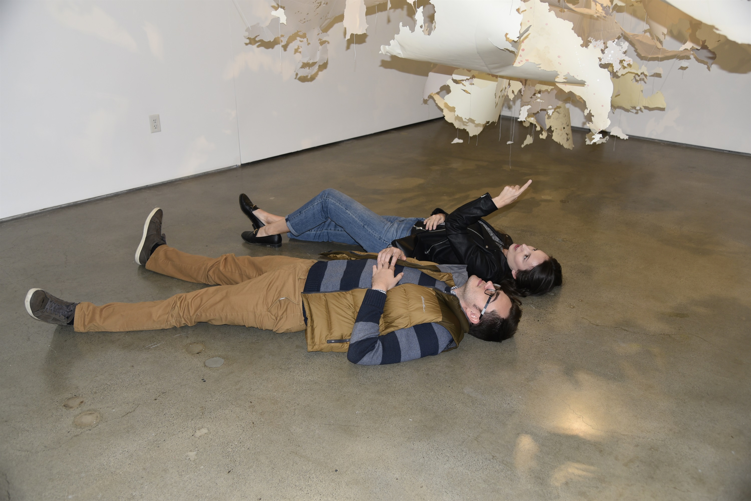 couple lying down looking at a Val Britton hanging paper art installation
