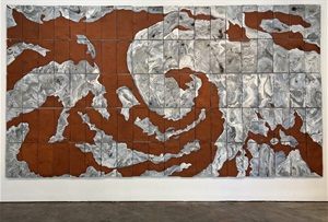 A glazed ceramic installation that is mounted on a wall featuring swirls of white glaze on red terracotta